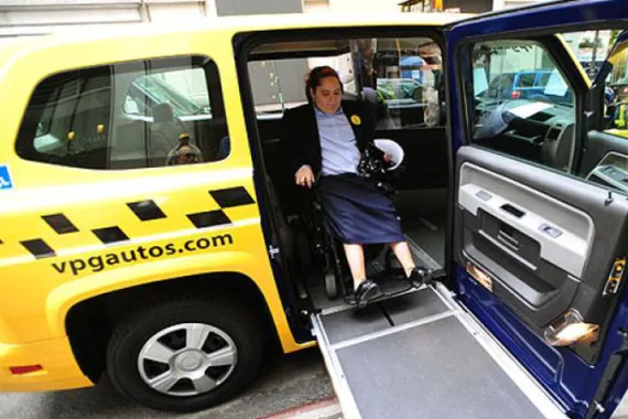 Wheelchair user exiting accessible taxi.