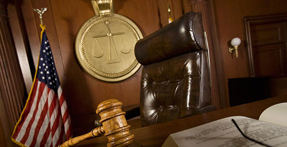 The Bench with gavel in foreground, empty chair and flag in background.