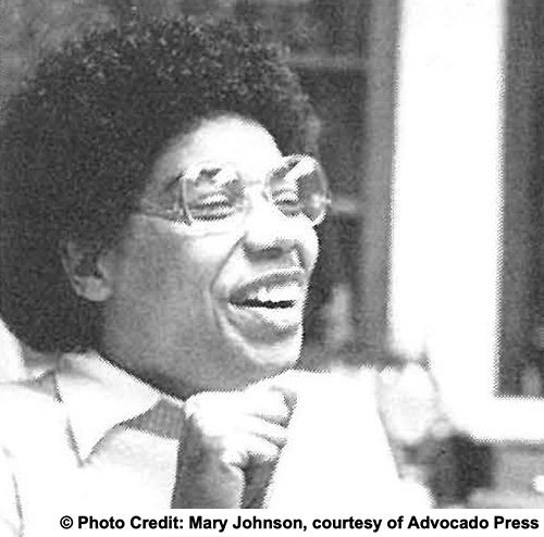 A woman seated outdoors laughing. Photo credit: Mary Johnson