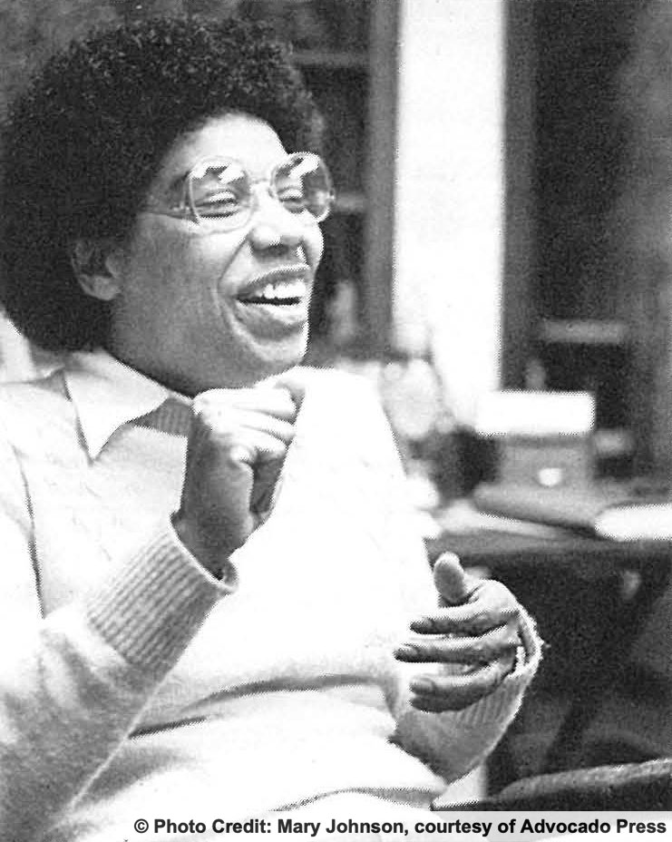 A woman seated outdoors laughing. Photo credit: Mary Johnson