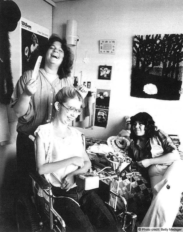 3 young women, one a wheelchair user are laughing it up in their dorm room. Photo credit: Betty Medsger
