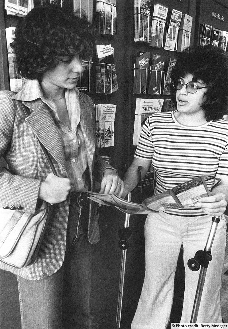 A woman using crutches for support shows another woman who is a customer. Photo credit: Betty Medsger