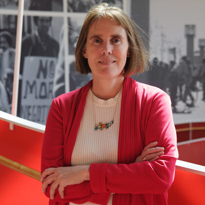 Linda Kilb with arms folded, smiling for the camera standing on the helical ramp at Ed Roberts Campus