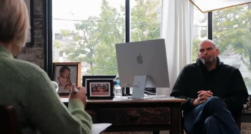 John Fetterman at his desk. Back of interviewer in foreground.