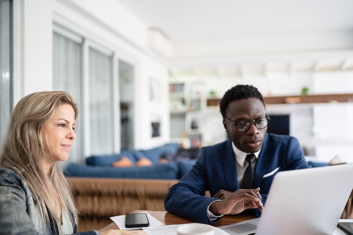 Two attorneys looks at a laptop screen together in an office space