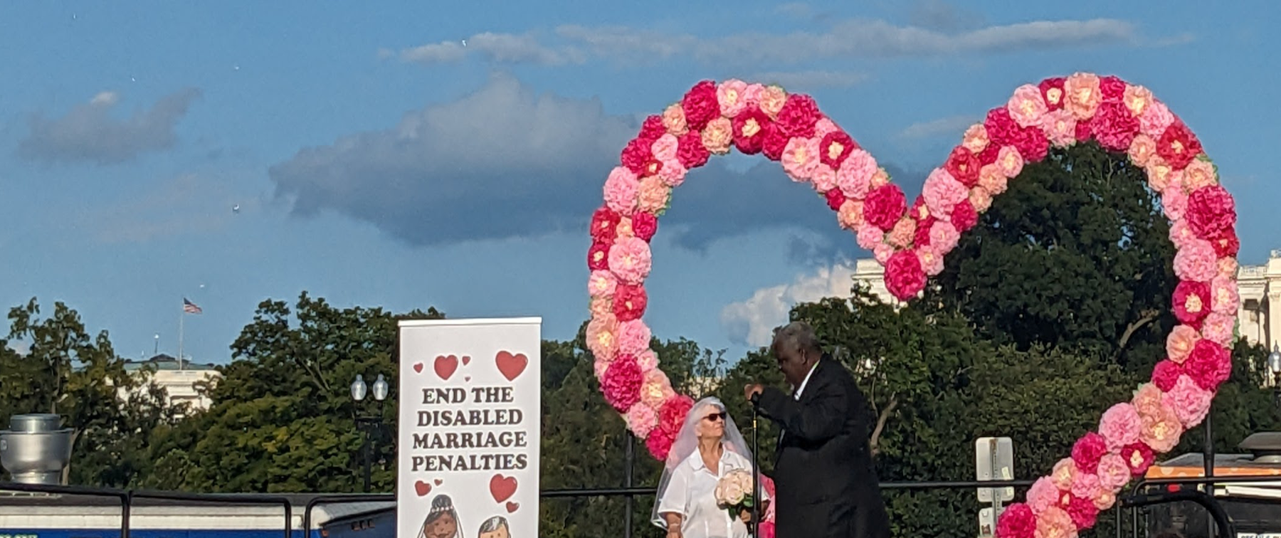 Donna and Ricardo Thorton on stage with a big pink heart balloon set up