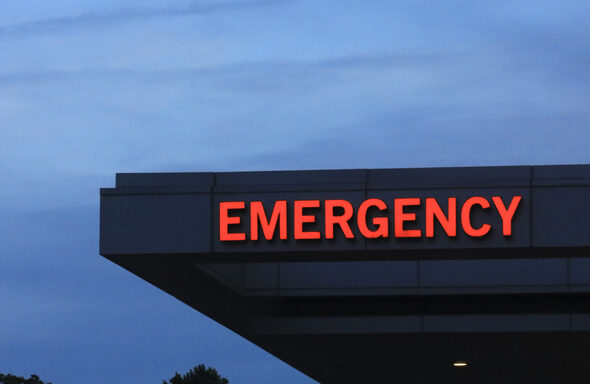 Hospital emergency room entrance sign against dark moody sky