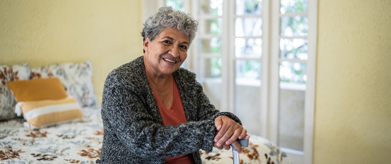An older woman sits in her bedroom