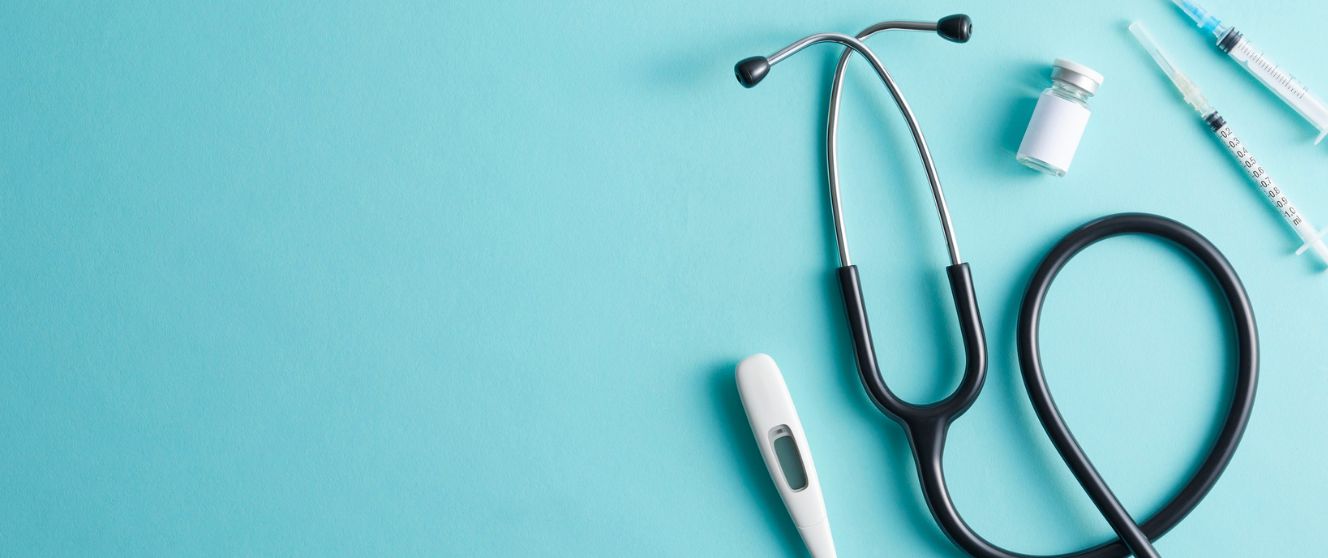 A stethoscope, thermometer and a vaccine on a blue background