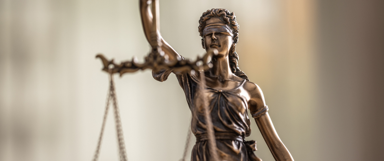 Bronze statue of lady justice with a blurry background