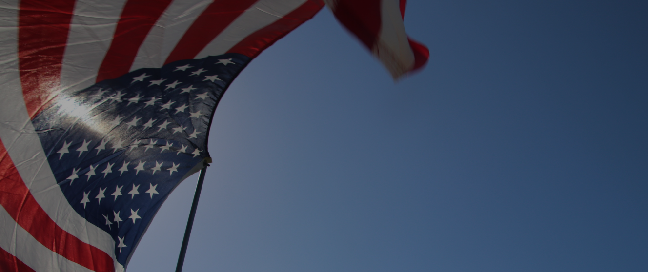 The American flag against a sky with a dark shade.