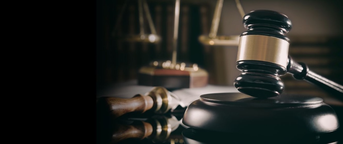 Close up of a courthouse gavel with the scales of justice blurry in the background
