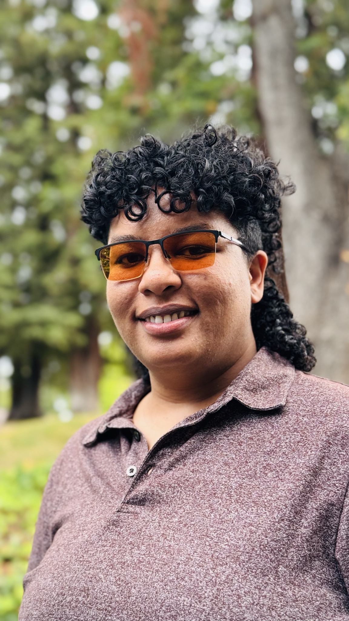Image of Khanstoshea Zingapan outdoors, black curly hair and tinted classes.