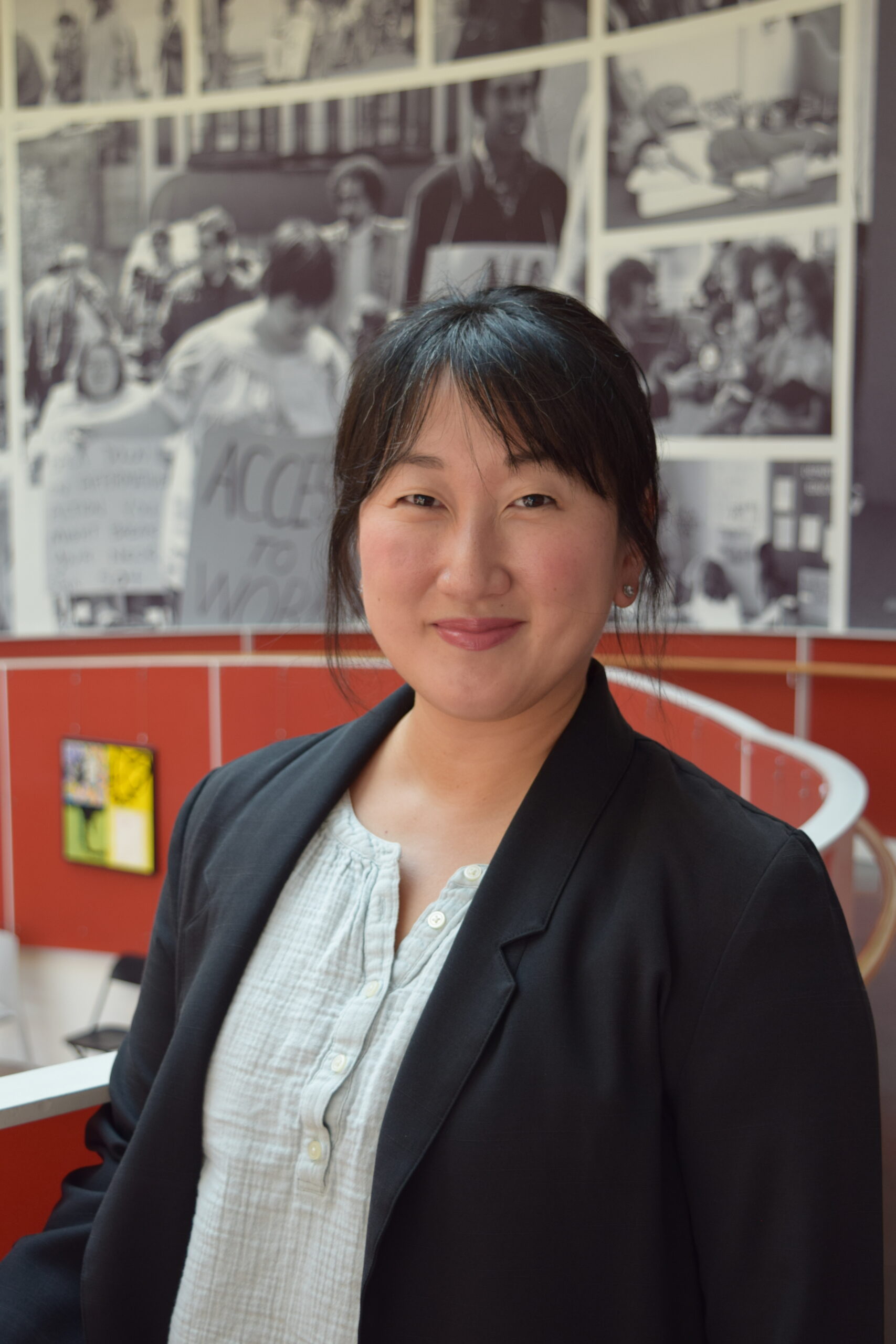 Portrait of Leah, an Asian woman in her 40s with black hair, wearing a light-colored shirt and dark suit jacket.