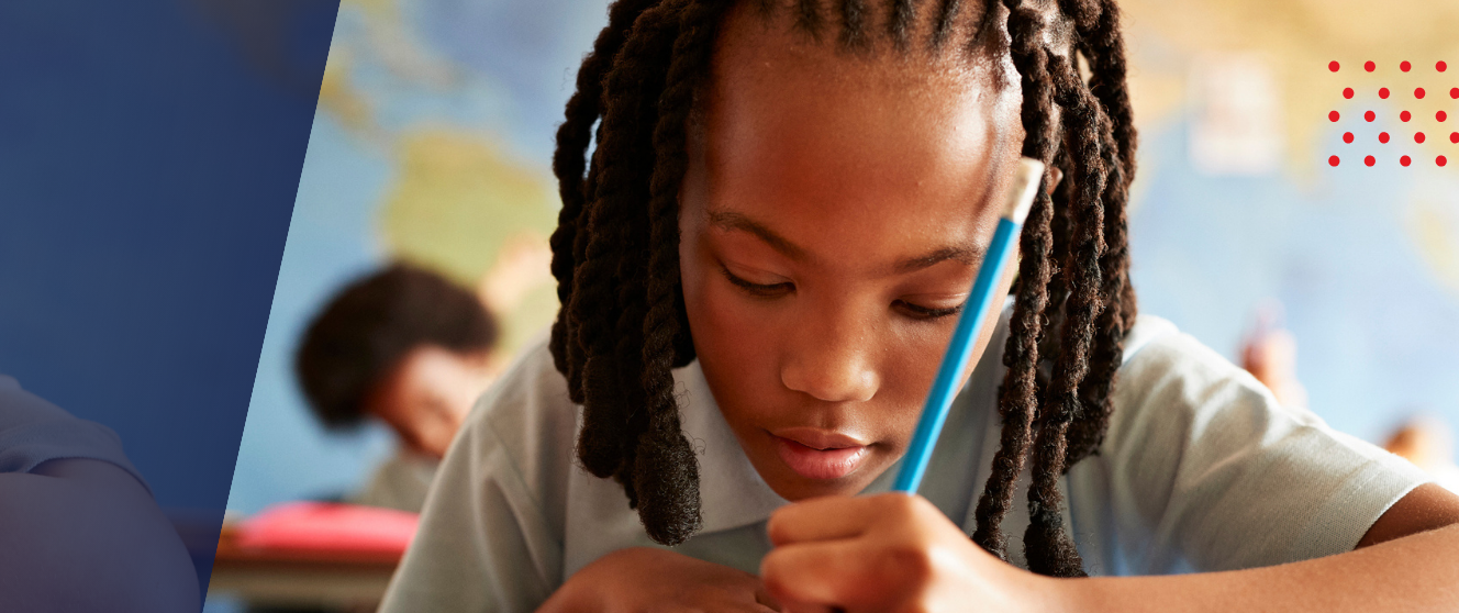 A young Black student writes with a pencil in a classroom