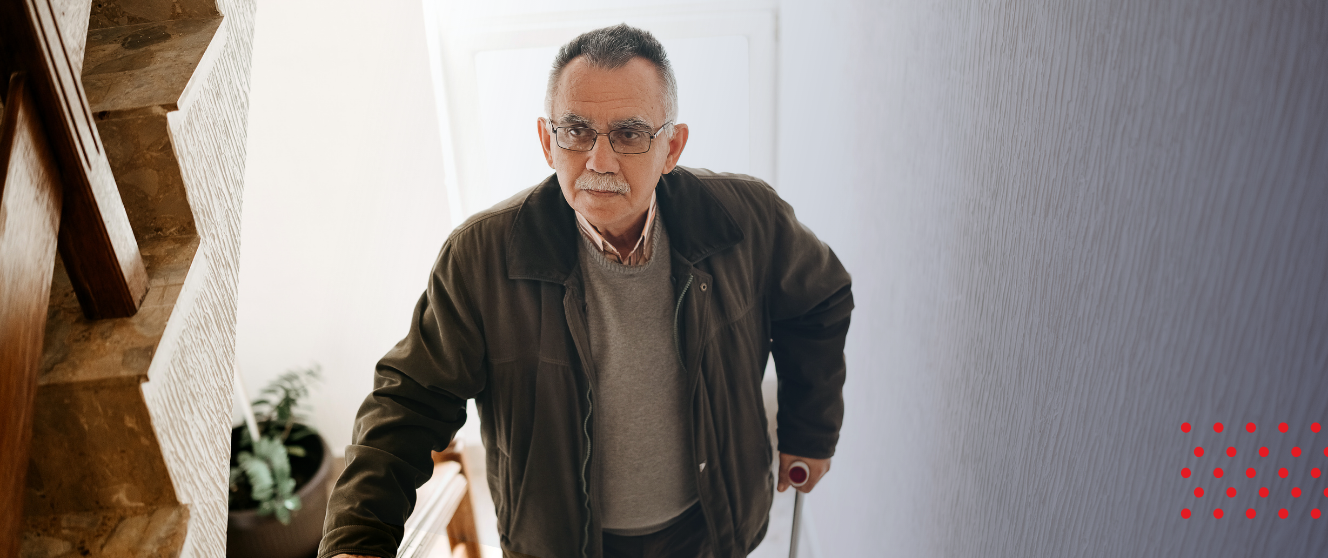 An older masculine presenting person climbing stairs in an apartment complex