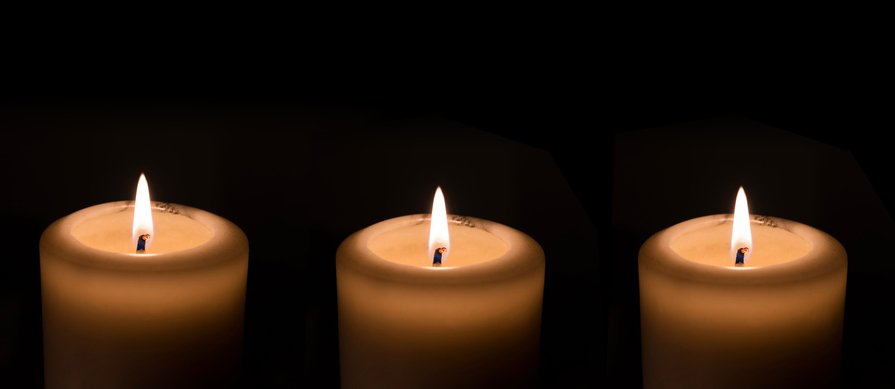 Three candles against a dark background