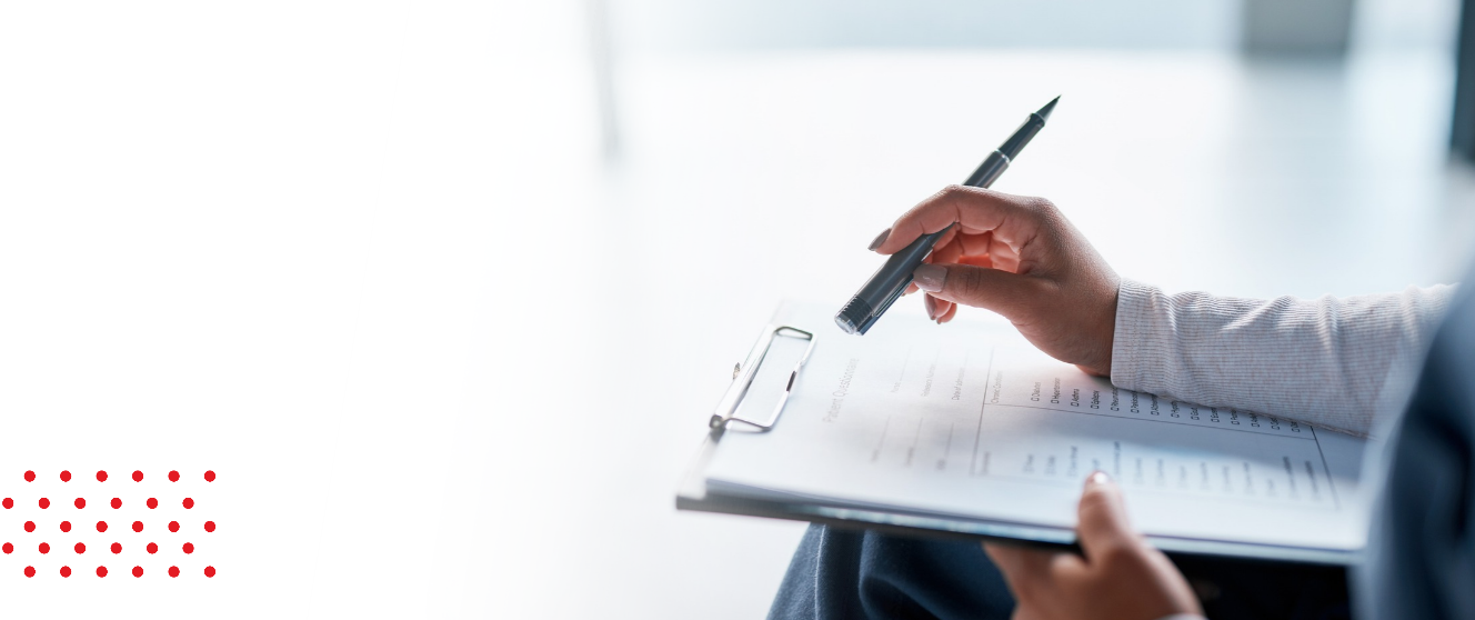 Close up of a clipboard on someone's lap, the person holds a pen