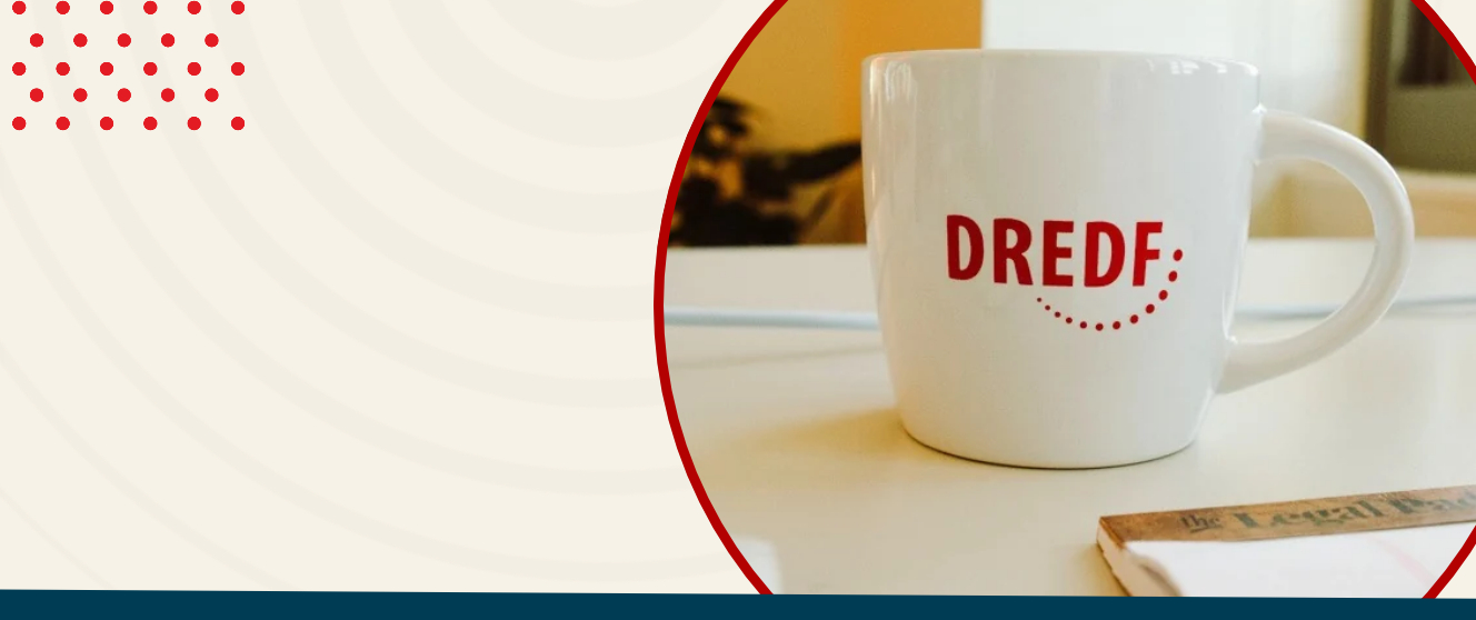 A coffee mug with the DREDF logo on it next to a legal pad