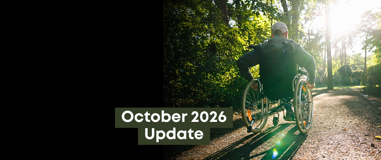 A wheelchair user travels along a tree-lined path in a public park as sunlight filters through the surrounding trees, the text on top reads 